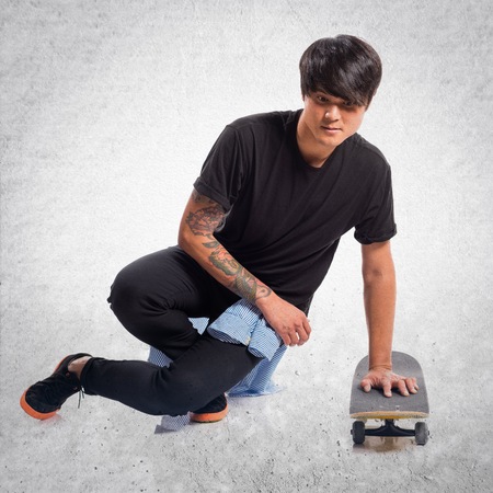 Asian urban man with skate on textured backgroundの写真素材