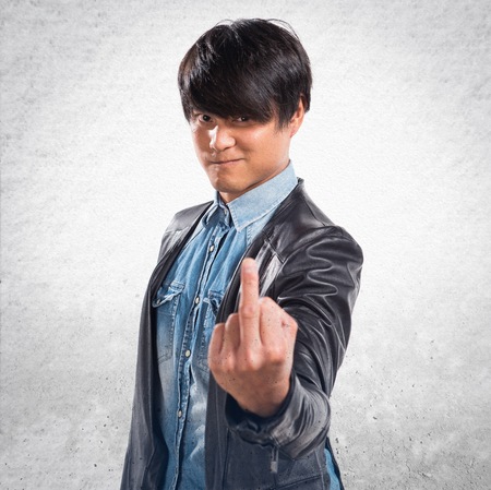 Asian handsome man making horn gesture on textured backgroundの写真素材