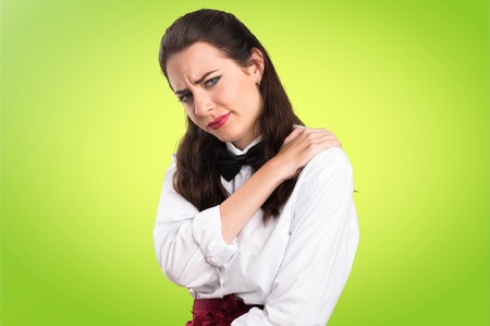 Young beautiful waitress with shoulder pain on colorful backgroundの写真素材