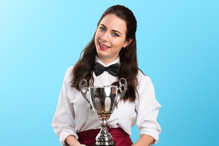 Young beautiful waitress holding a trophy on colorful backgroundの写真素材