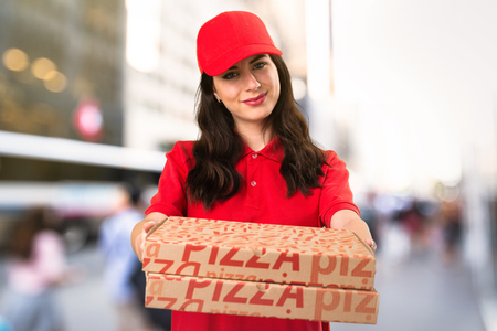 Happy pizza delivery woman on unfocused backgroundの写真素材