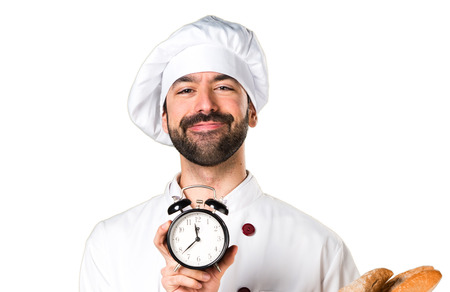 Young baker holding some bread and holding vintage clockの写真素材