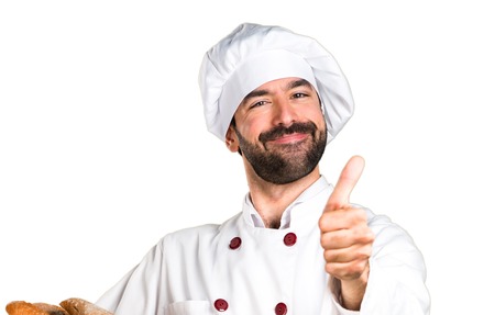 Young baker holding some bread and with thumb up