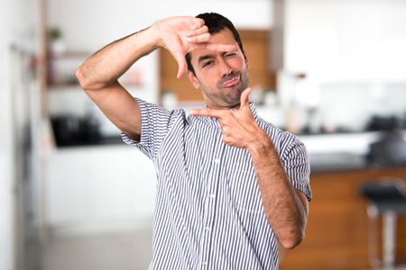 Handsome man focusing with his fingers inside houseの写真素材