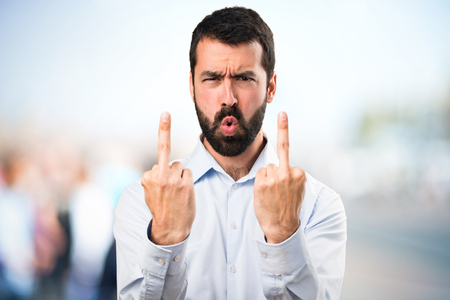 Handsome man with beard making horn gesture on unfocused backgroundの写真素材