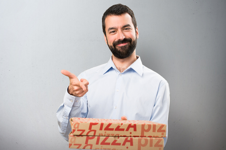 Happy Handsome man with beard holding pizzas on textured backgroundの写真素材