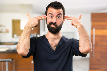 Handsome man with beard making gun gesture inside house