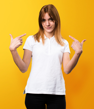 Beautiful young girl proud of herself on yellow backgroundの写真素材