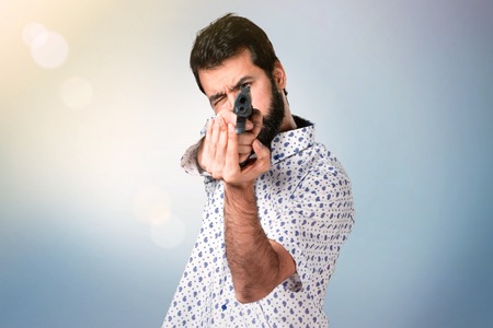 Handsome brunette man with beard holding a pistolの写真素材