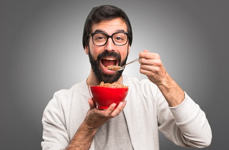 Happy Hipster man holding a bowl of cereals on grey backgroundの写真素材