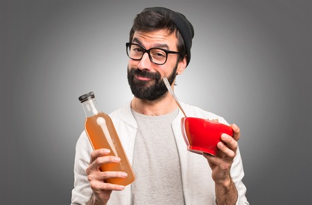 Happy Hipster man holding an orange juice on grey backgroundの写真素材