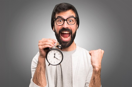 Happy Hipster man holding vintage clock on grey backgroundの写真素材