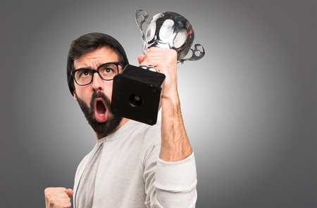 Happy Hipster man holding a trophy on grey backgroundの写真素材