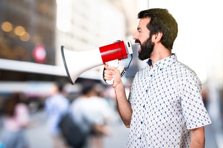 Handsome brunette man with beard shouting by megaphoneの写真素材