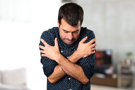 Brunette man freezing inside houseの写真素材