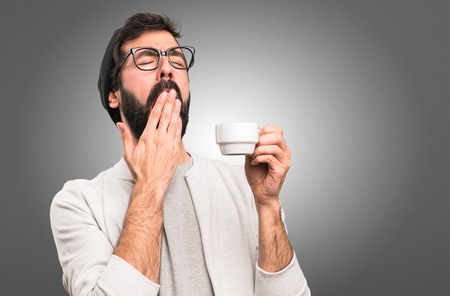 Hipster man holding a cup of coffee on grey backgroundの写真素材
