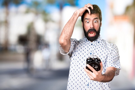 Handsome brunette man with beard holding vintage clockの写真素材