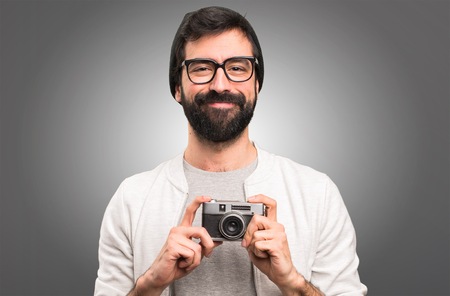 Happy Hipster man holding a camera on grey backgroundの写真素材