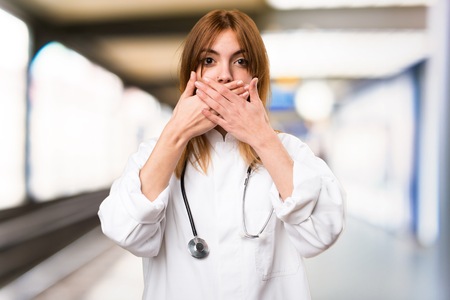 Young doctor woman covering her mouth in the hospitalの写真素材
