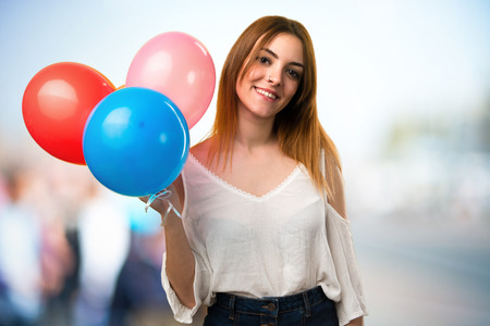 Happy beautiful young girl holding a balloon on unfocused backgroundの写真素材