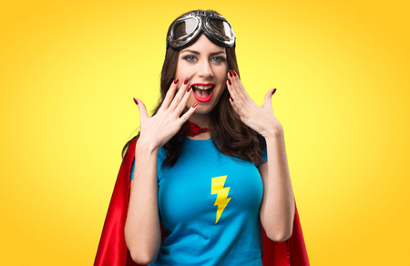 Pretty superhero girl making surprise gesture on colorful background