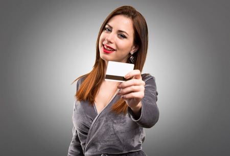 Beautiful young girl holding a credit card on textured backgroundの写真素材