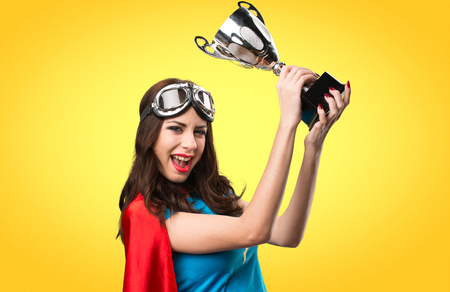 Pretty superhero girl holding a trophy on colorful backgroundの写真素材