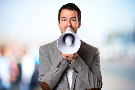 Handsome man holding a megaphone on unfocused backgroundの写真素材