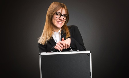 Young business woman holding a briefcase on dark background