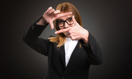 Young business woman focusing with her fingers on dark background