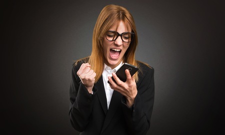 Young business woman talking to mobile on dark backgroundの写真素材