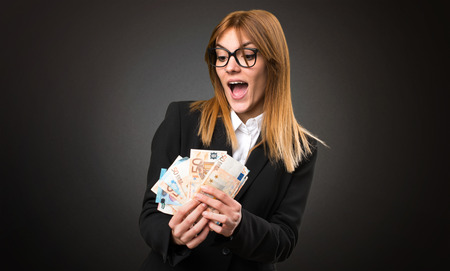 Young business woman taking a lot of money on dark background