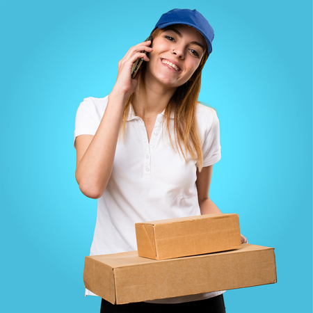 Delivery woman talking to mobile on colorful backgroundの写真素材