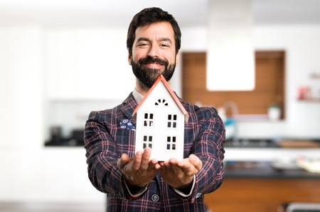 Happy Well dressed man holding a little house inside houseの写真素材