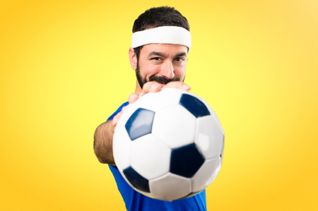 Funny sportsman holding a soccer ball on colorful backgroundの写真素材