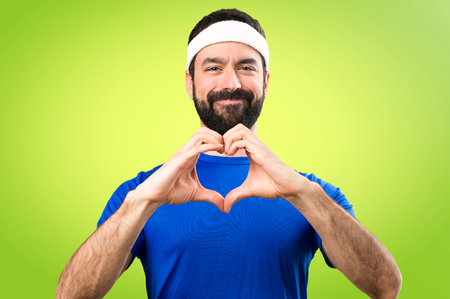 Funny sportsman making a heart with his hands on colorful backgroundの写真素材