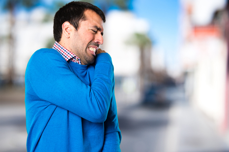 Handsome young man with shoulder pain on unfocused backgroundの写真素材