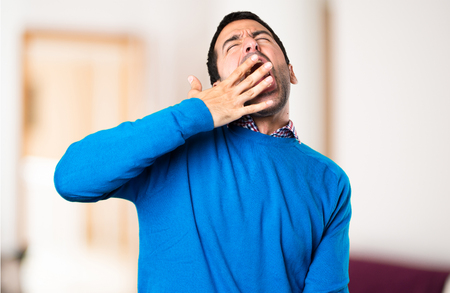 Handsome young man yawning on unfocused backgroundの写真素材