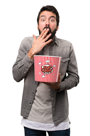 Surprised Handsome man with beard eating popcorns on white backgroundの写真素材