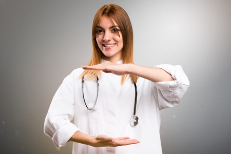 Young doctor woman holding something on grey backgroundの写真素材