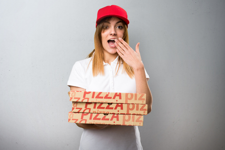 Pizza delivery woman making surprise gesture on textured backgroundの写真素材