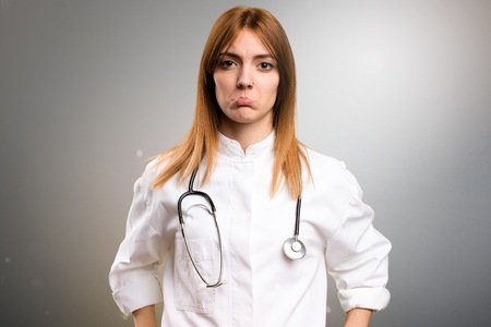 Sad young doctor woman on grey backgroundの写真素材