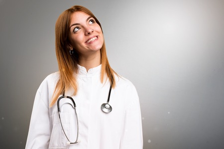 Young doctor woman looking up on grey backgroundの写真素材