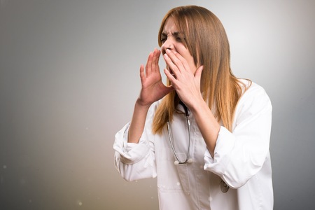 Young doctor woman shouting on grey backgroundの写真素材