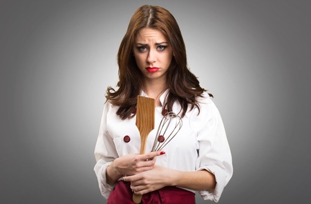 Sad beautiful chef woman on grey backgroundの写真素材