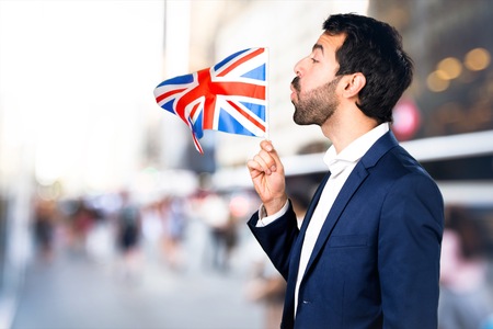 Handsome man holding an UK flag on unfocused backgroundの写真素材