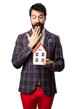 Surprised Well dressed man holding a little house on white backgroundの写真素材