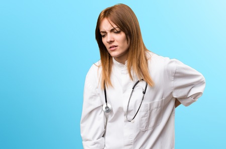 Young doctor woman with back pain on colorful background