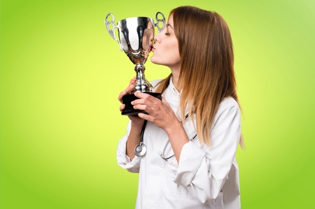 Young doctor woman holding a trophy on colorful backgroundの写真素材