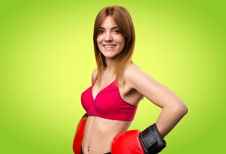 Young sport woman with boxing gloves on colorful backgroundの写真素材